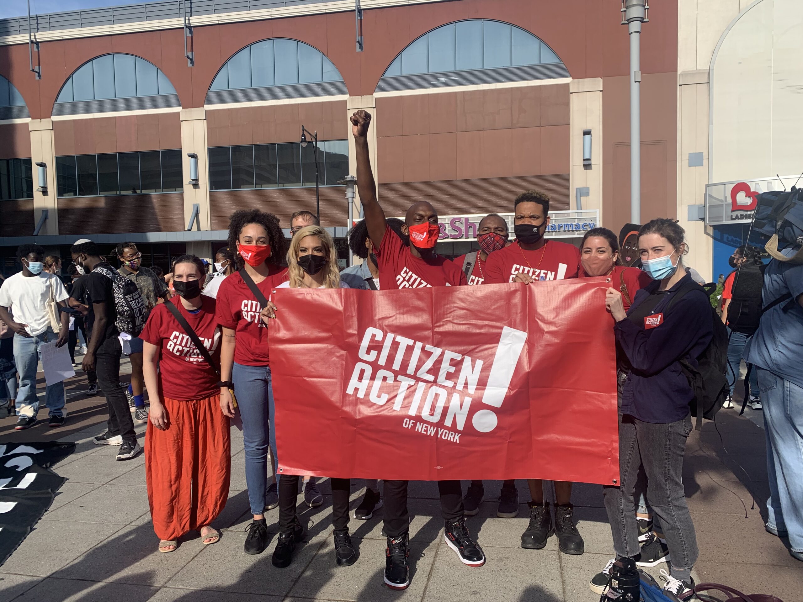A group of Citizen Action staff and members holding a red banner at a rally.